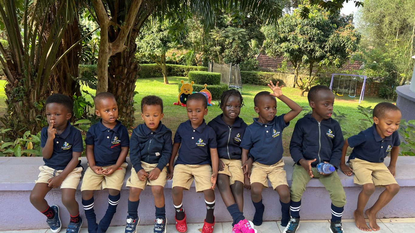 Children in navy uniforms sitting on a garden wall